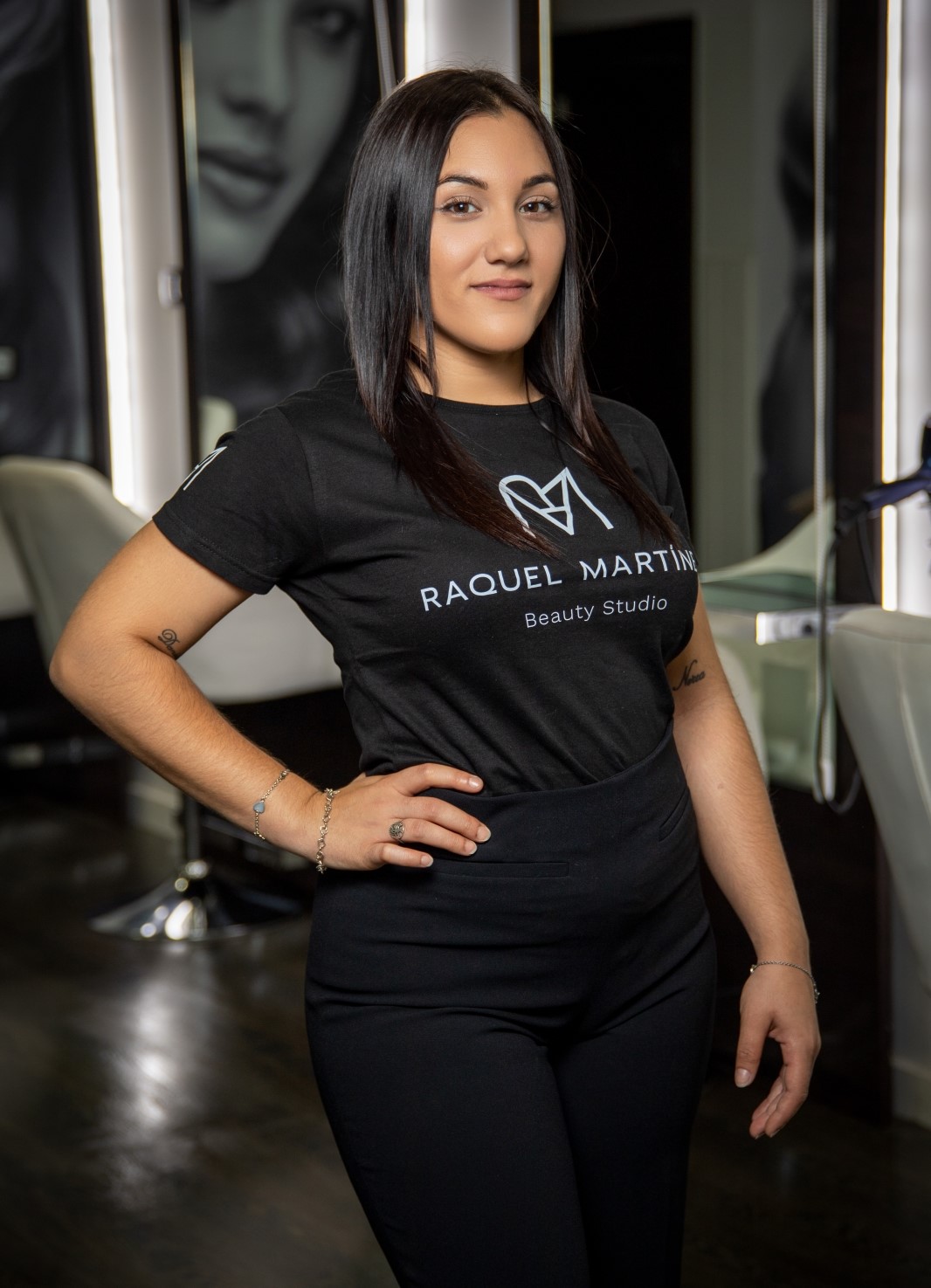joven morena con la mano en la cintura y la camiseta de la peluqueria