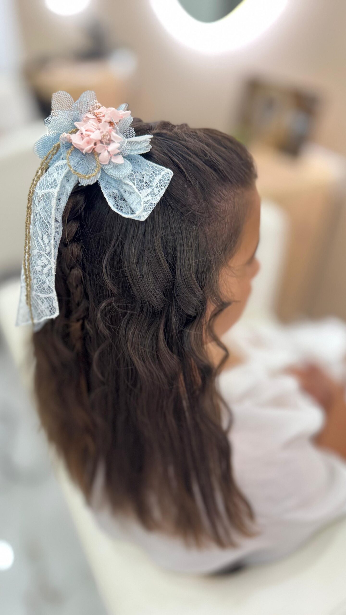 niña vista de perfil con un lazo azul en el pelo, peinada para una comunion