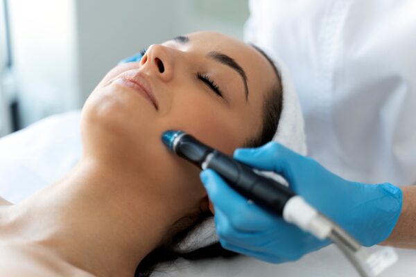 una profesional dando un tratamiento facial a la cara de una joven